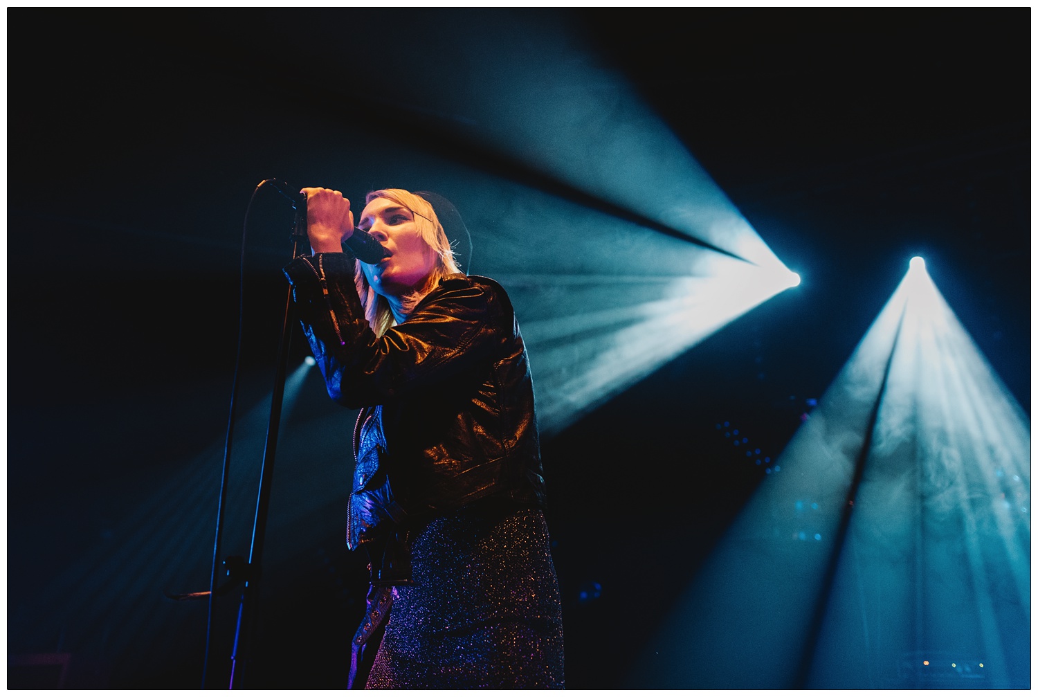 Faith Vern singing on stage in the lights in the band Pins