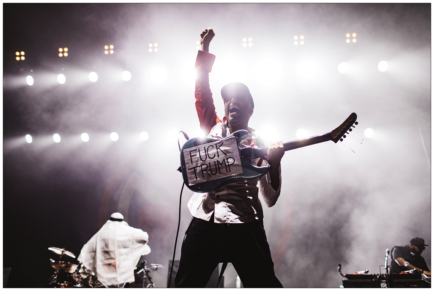 Tom Morello holding up his Arm the Homeless guitar with a Fuck Trump sign on the back.