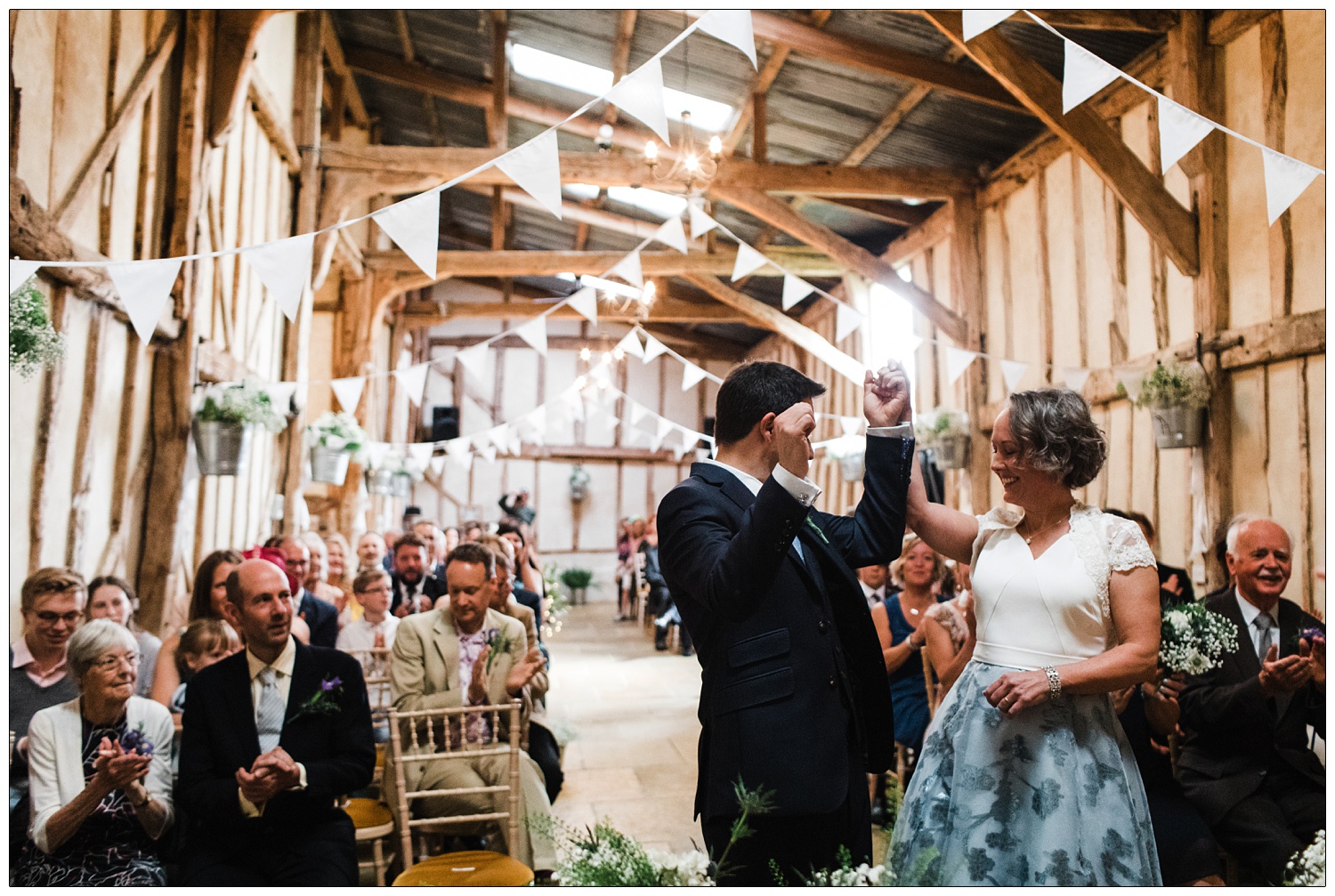 Bride and groom holding hands and raise them in the air to celebrate just getting married.