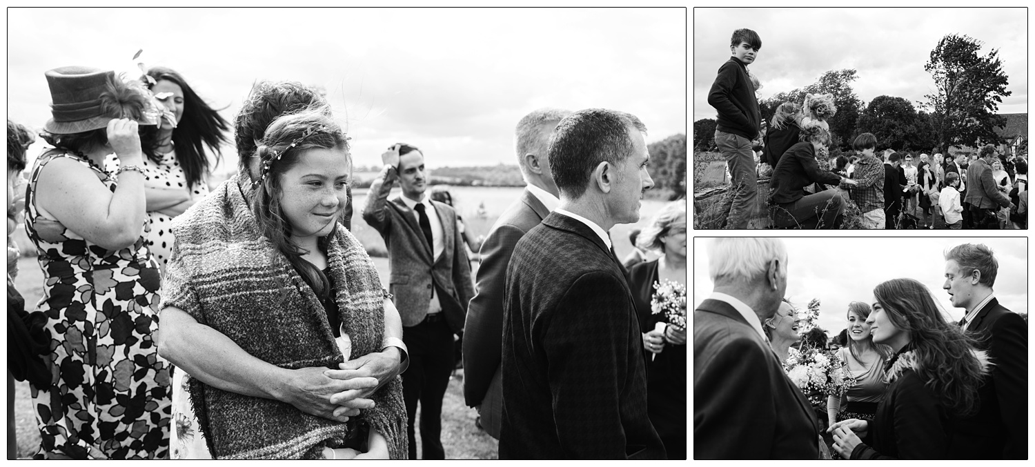 Candid photographs at a wedding. Just after the ceremony everyone has gone outside. A woman hugs a girl wrapped in a blanket. Children climb the tree trunk.