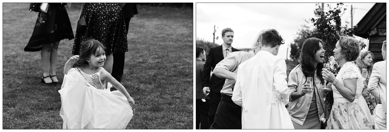 Candid moments out in the stack yard wedding garden at a venue in Alpheton in Suffolk. Bride is laughing with a friend. A little girl is twirling in her dress.