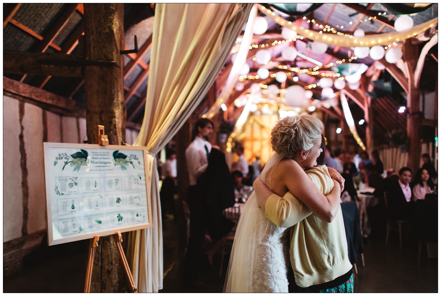 The bride hugging a guest next to the table plan.