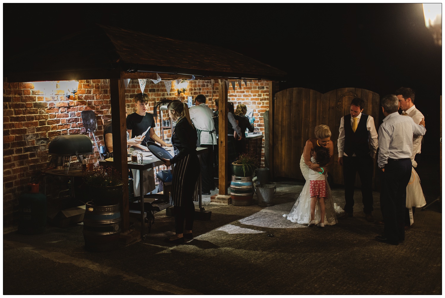 Staff making pizzas outside and the bride is hugging a child at Alpheton Hall Barns.