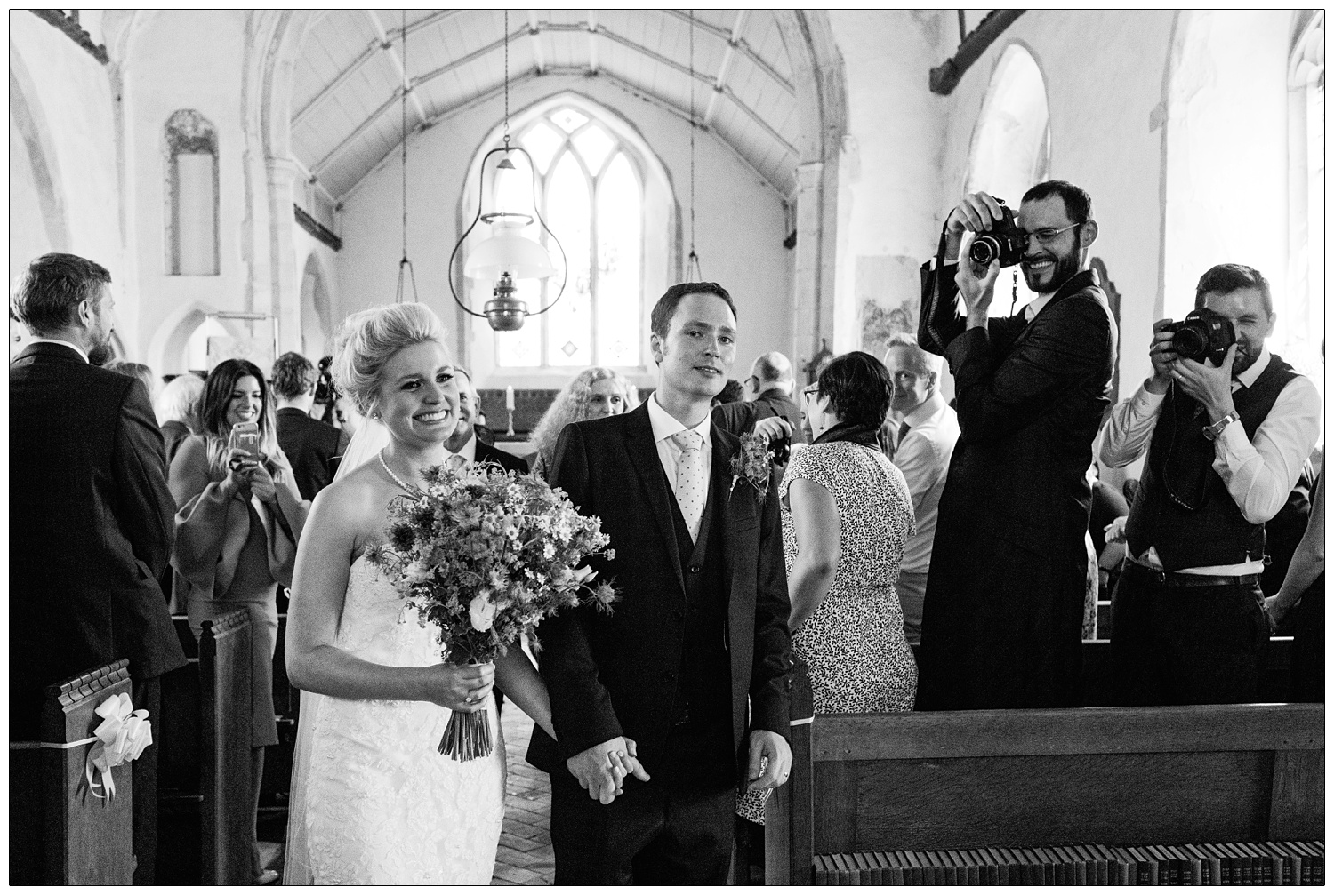 Bride and groom walking down the aisle after getting married in St Peter & St Paul's Church in Alpheton