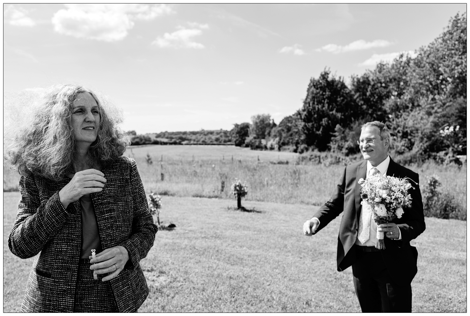 A woman on the left, hair in the wind. Man holding flowers.