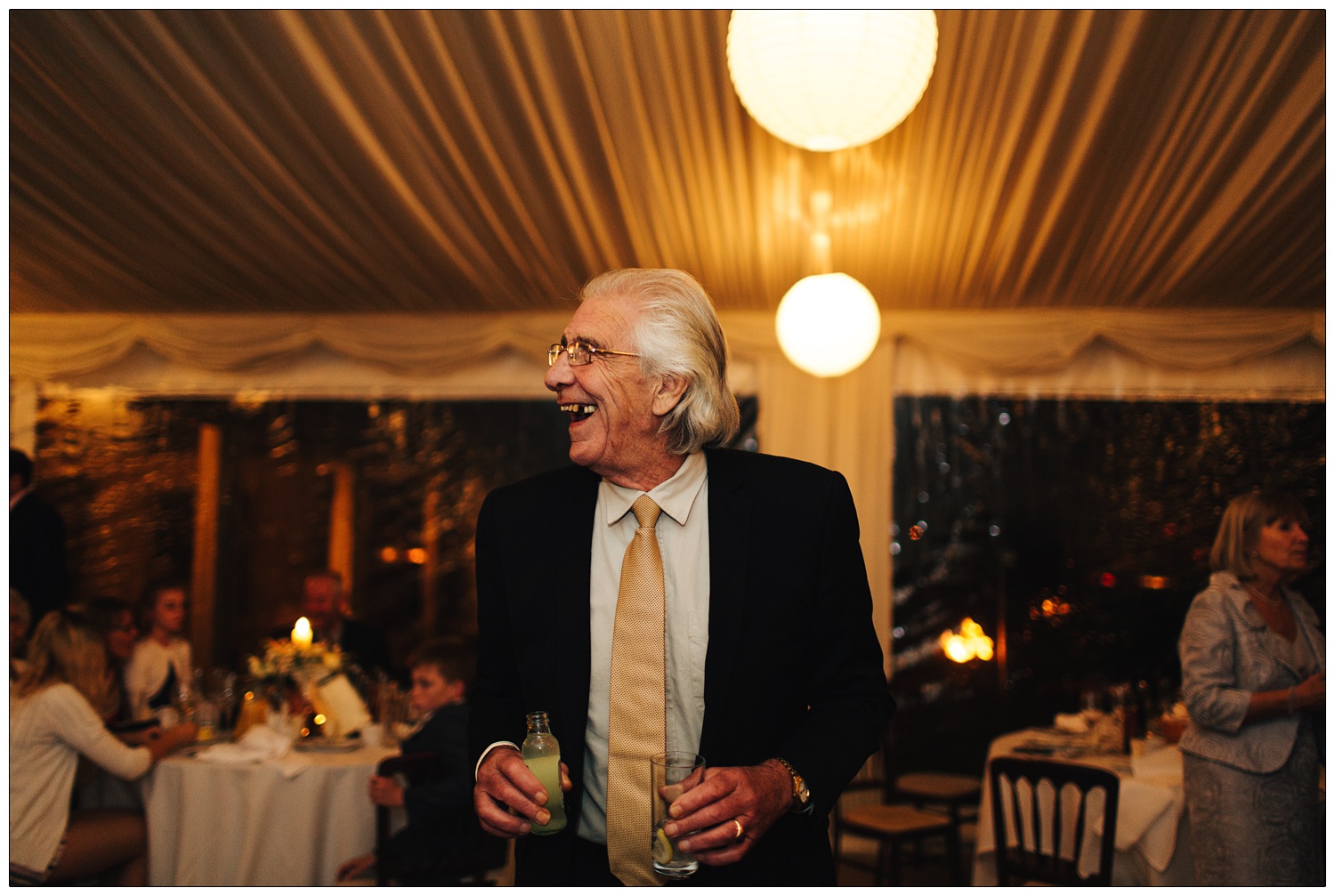 Man holding a drink and smiling at a wedding