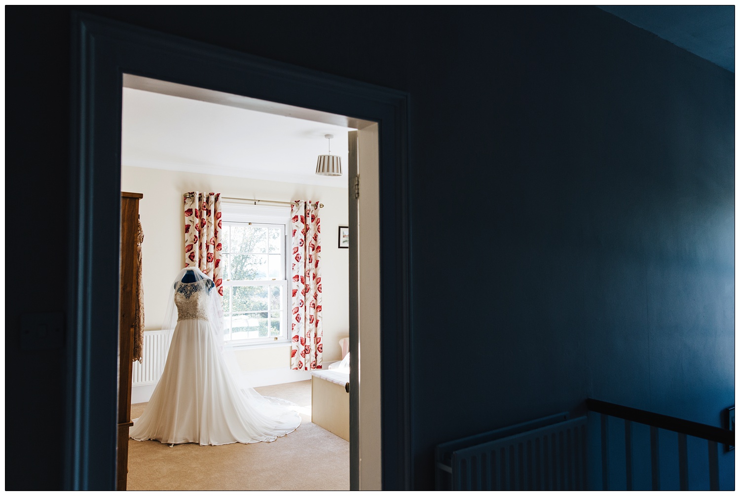Wedding dress on a mannequin in a bedroom seen through a door.