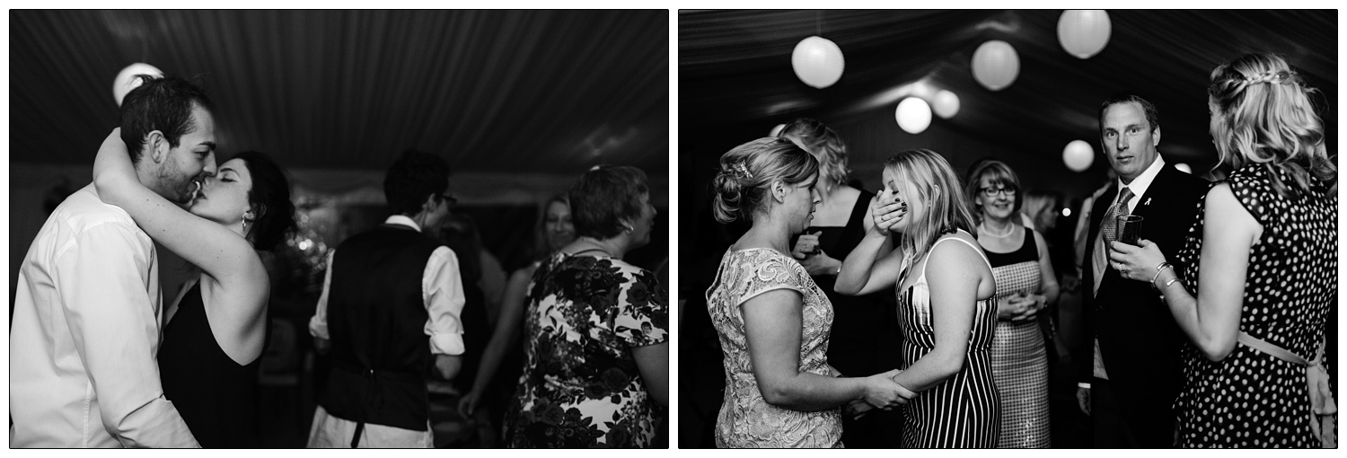 black and white photograph of people at wedding reception. A couple are kissing.