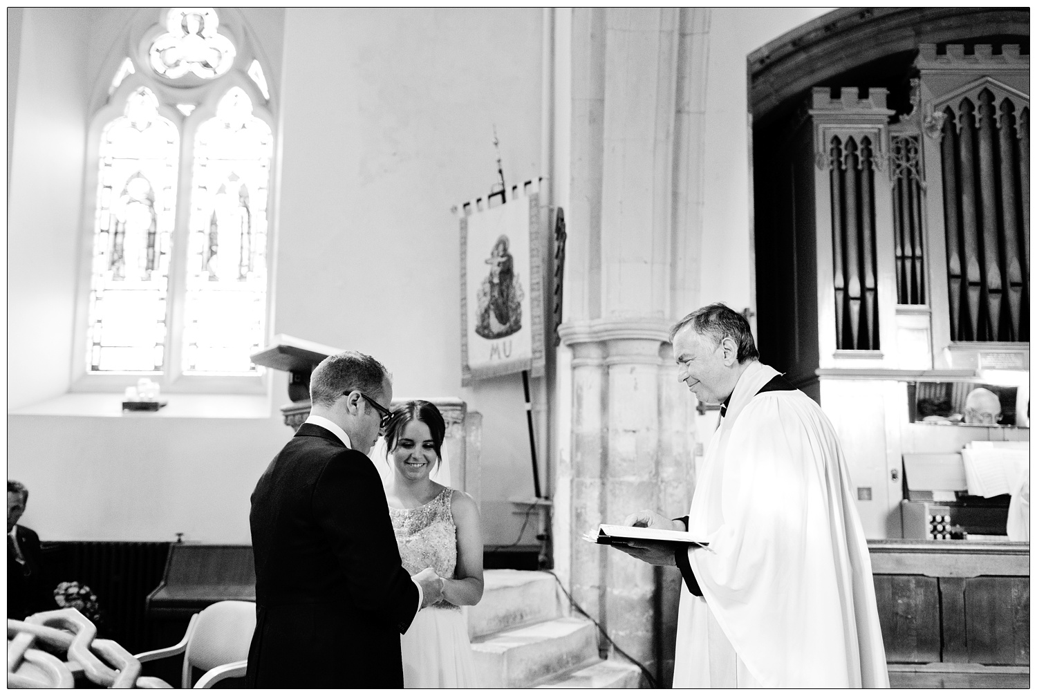 Bride, groom and vicar during wedding ceremony at St Thomas' Church Bradwell-on-Sea. The pipe organ is on the right.