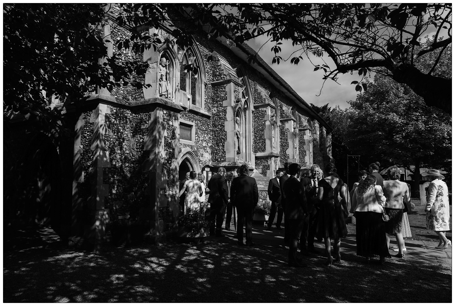Black and white photograph of people outside St Peter's Church in Maldon. Trees can be seen at the top and left.