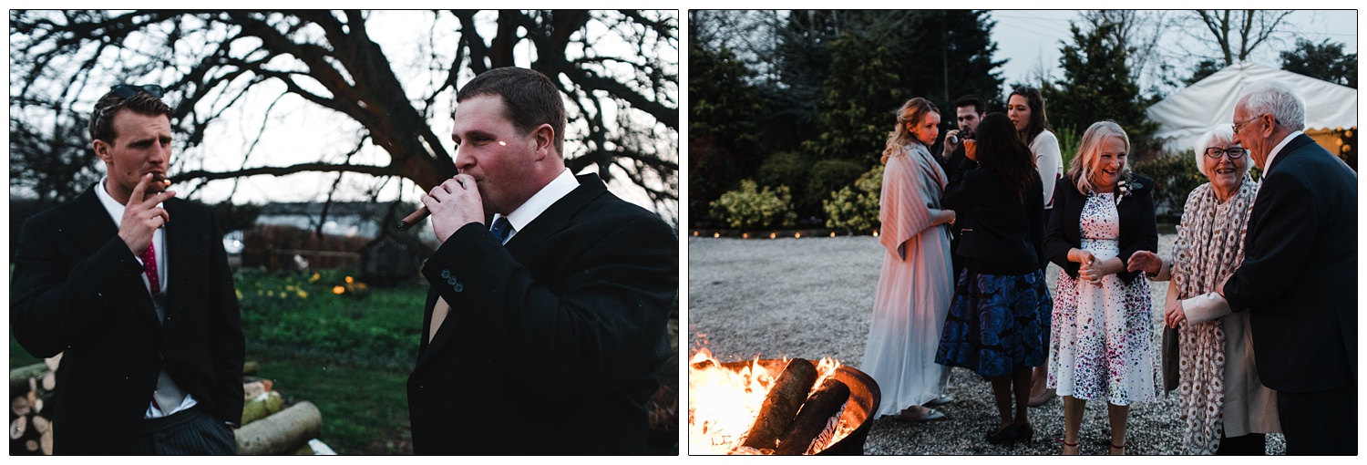 Men smoking cigars at wedding. People round a firepit.