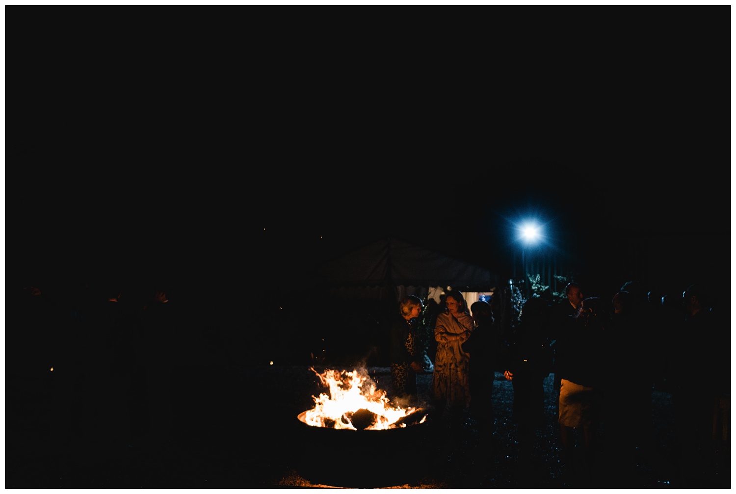 Firepit at night with wedding guests gathered around