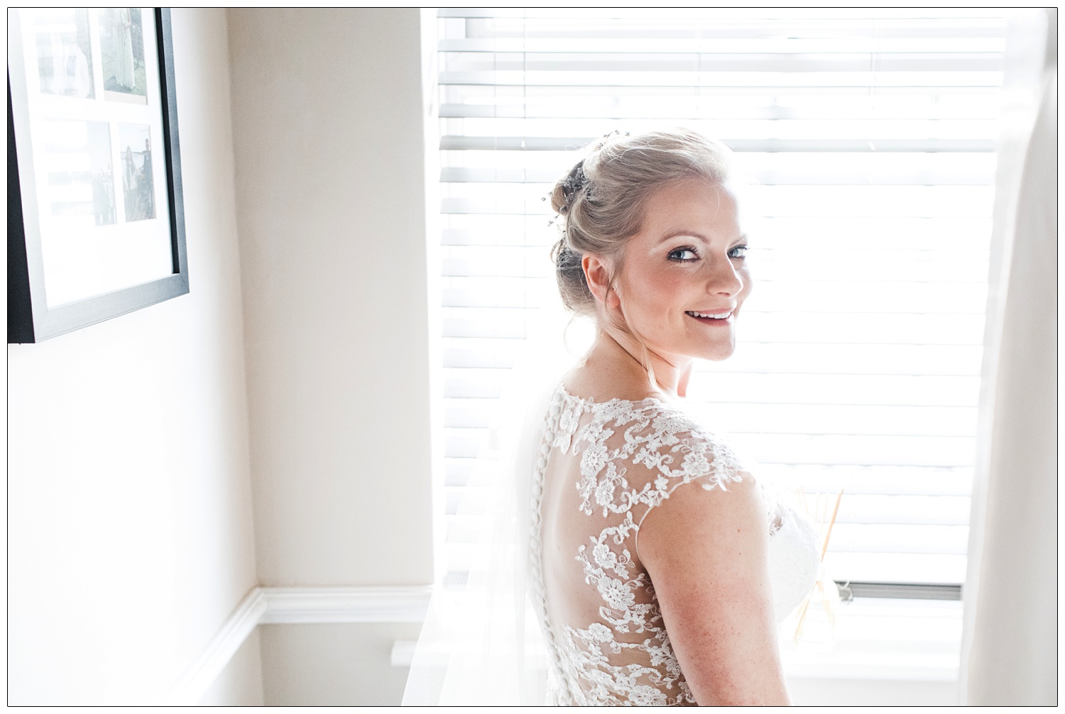 Bride at home looking at the camera in front of venetian blinds.