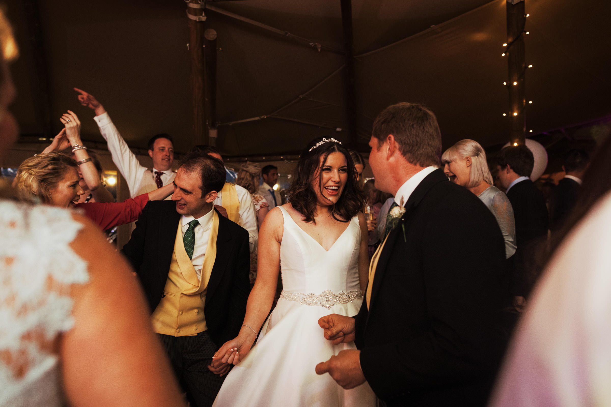 Bride and groom dancing with guests at their Essex wedding in a tipi on a farm.
