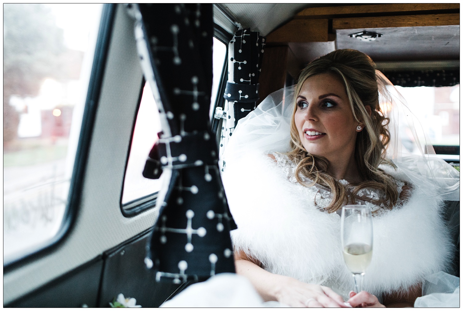 Bride in a camper van holding a champagne flute.