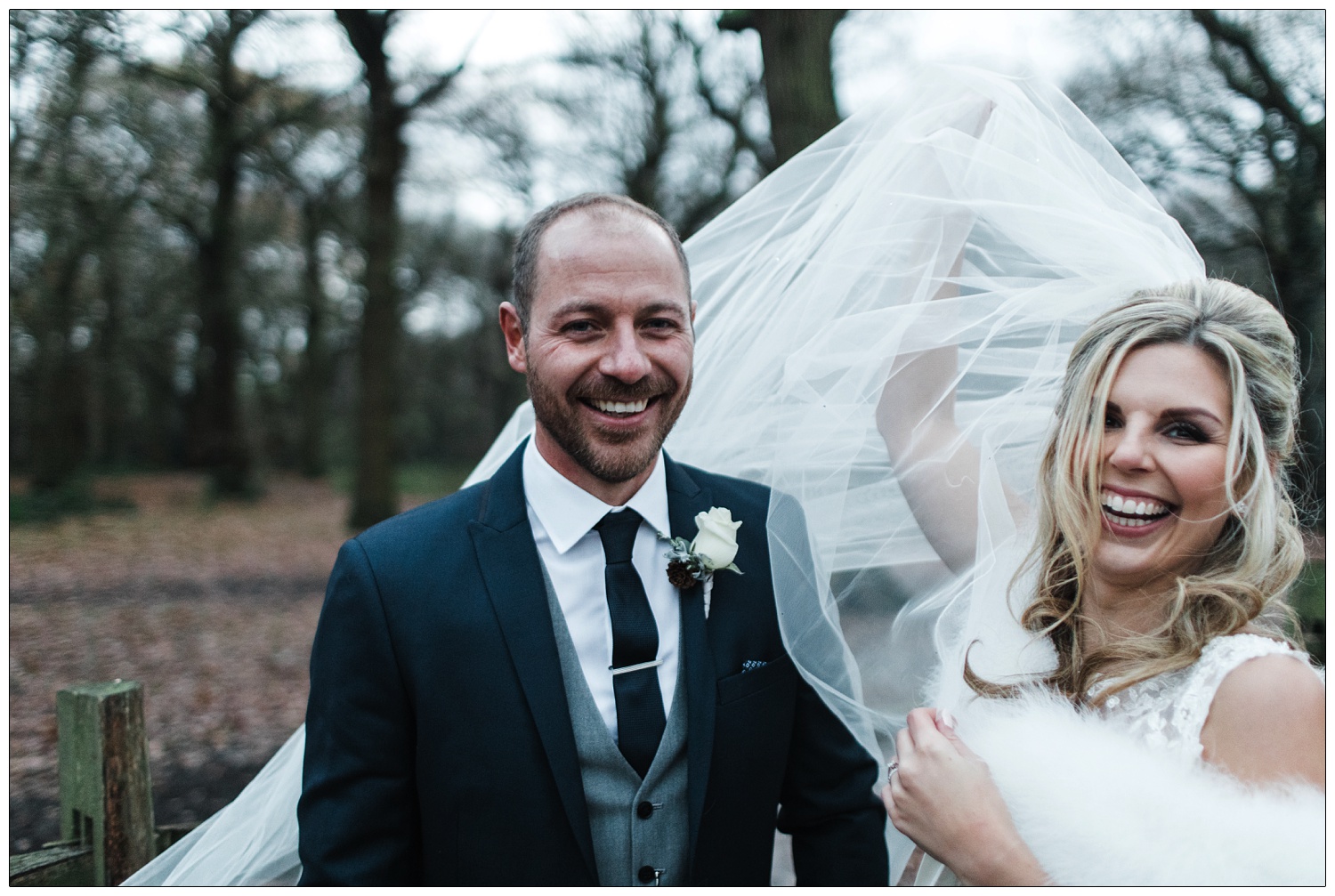 Bride and groom in a photograph in Hockley woods in December. The wind is blowing the brides veil and it's starting to get dark..