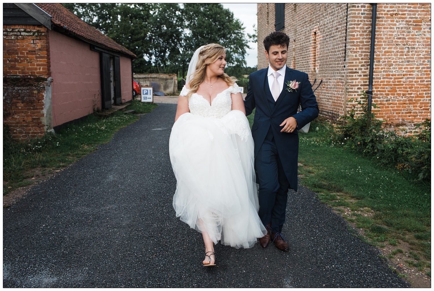 Bride and groom walking along together outside.