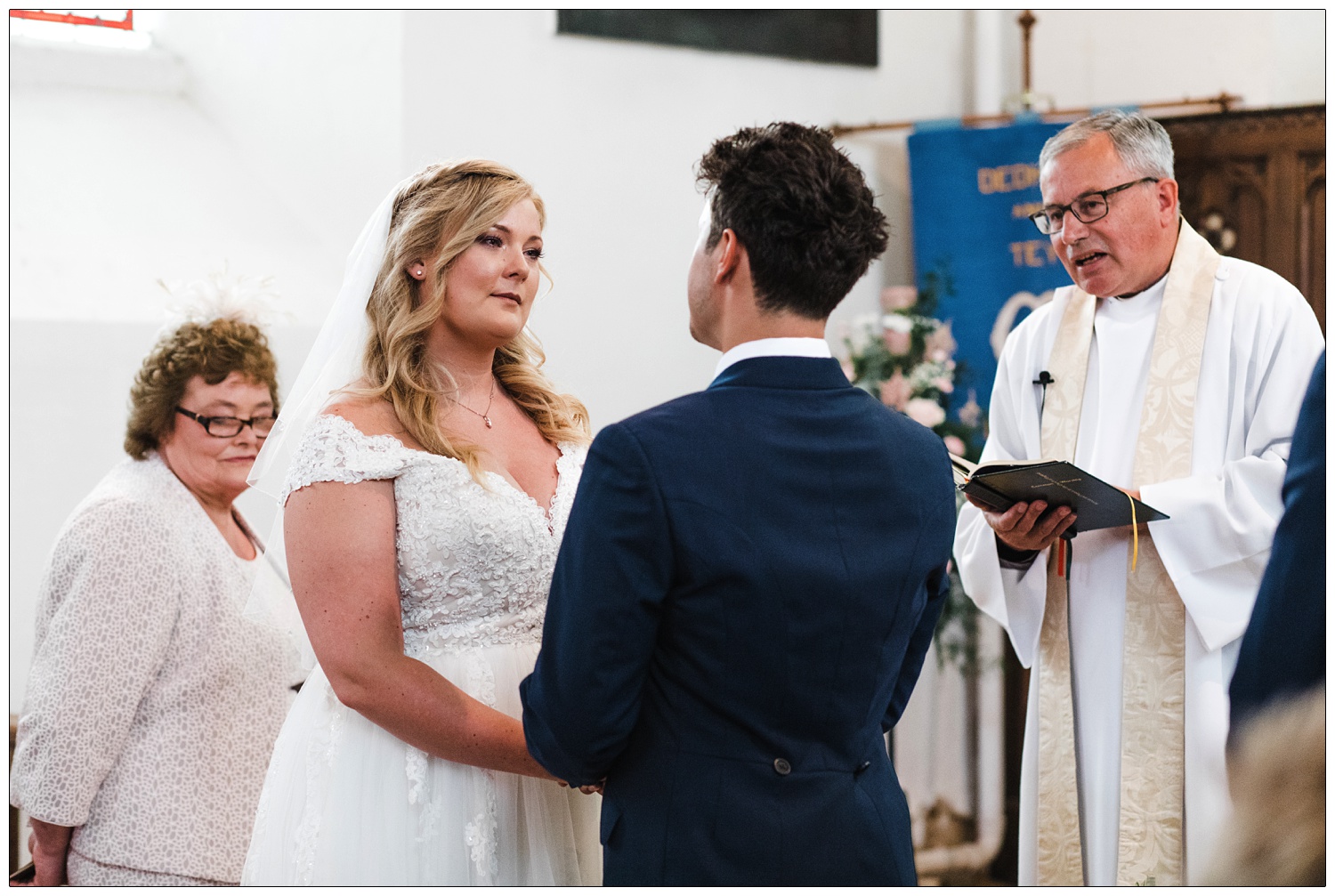 Woman looking at man whilst taking wedding vows in St Barnabas Church in Great Tey.