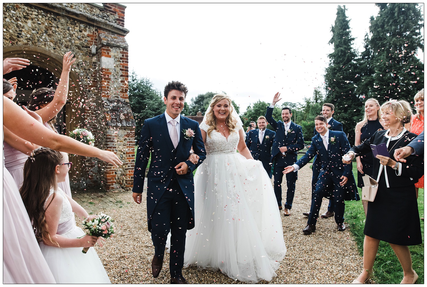 Just married couple covered in confetti their friends and family are throwing.