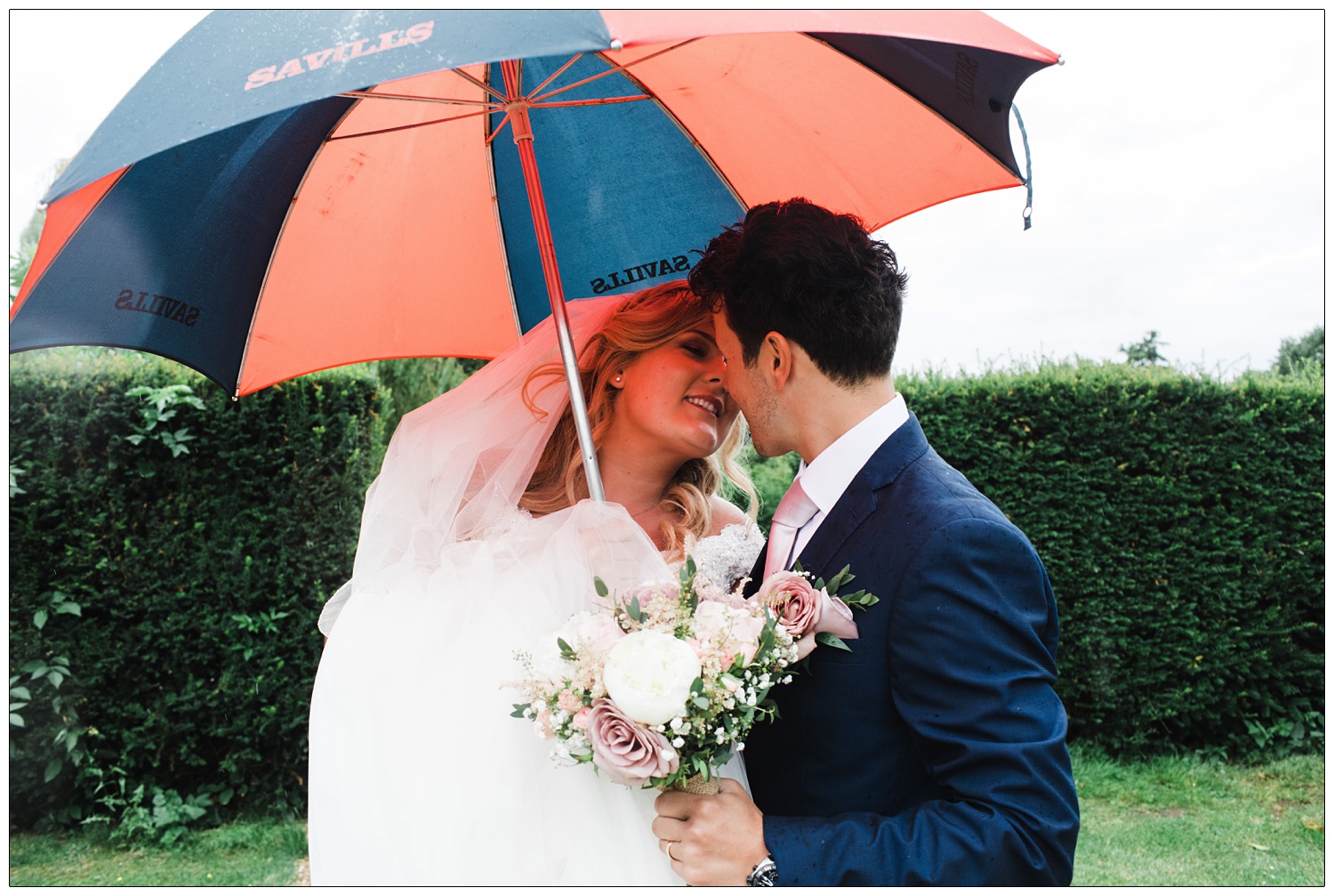 Bride and groom about to kiss under an umbrella.