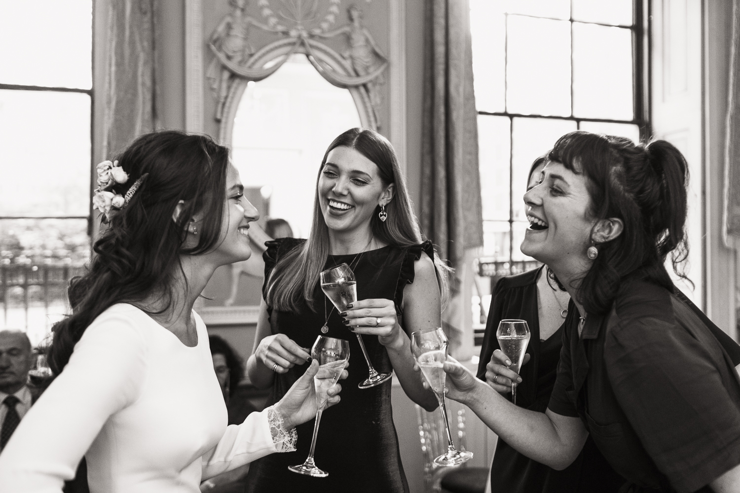 Women at a wedding pretending to laugh naturally. A reception at Home House in London.