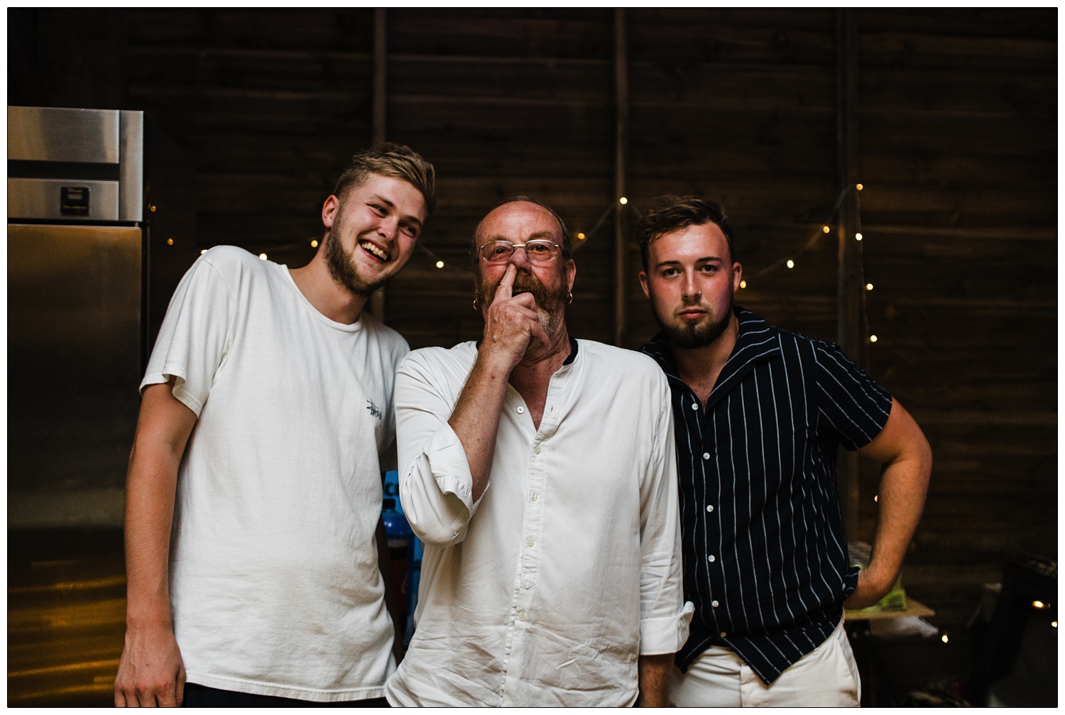 Three men, the middle one is picking his nose.