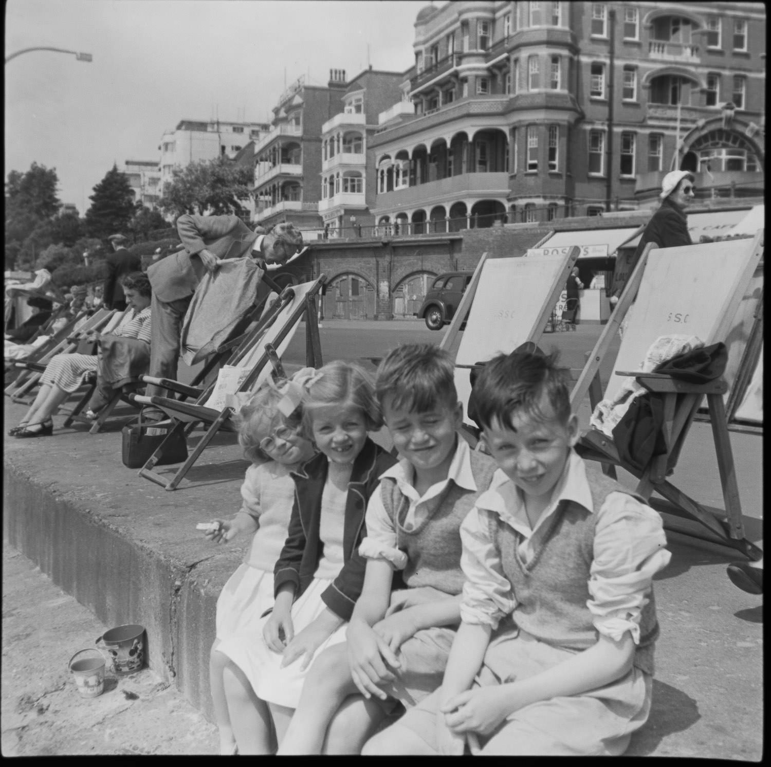 Children sitting down by the beach in Southend. A Rossi ice cream shop behind them. It's the 1950s.