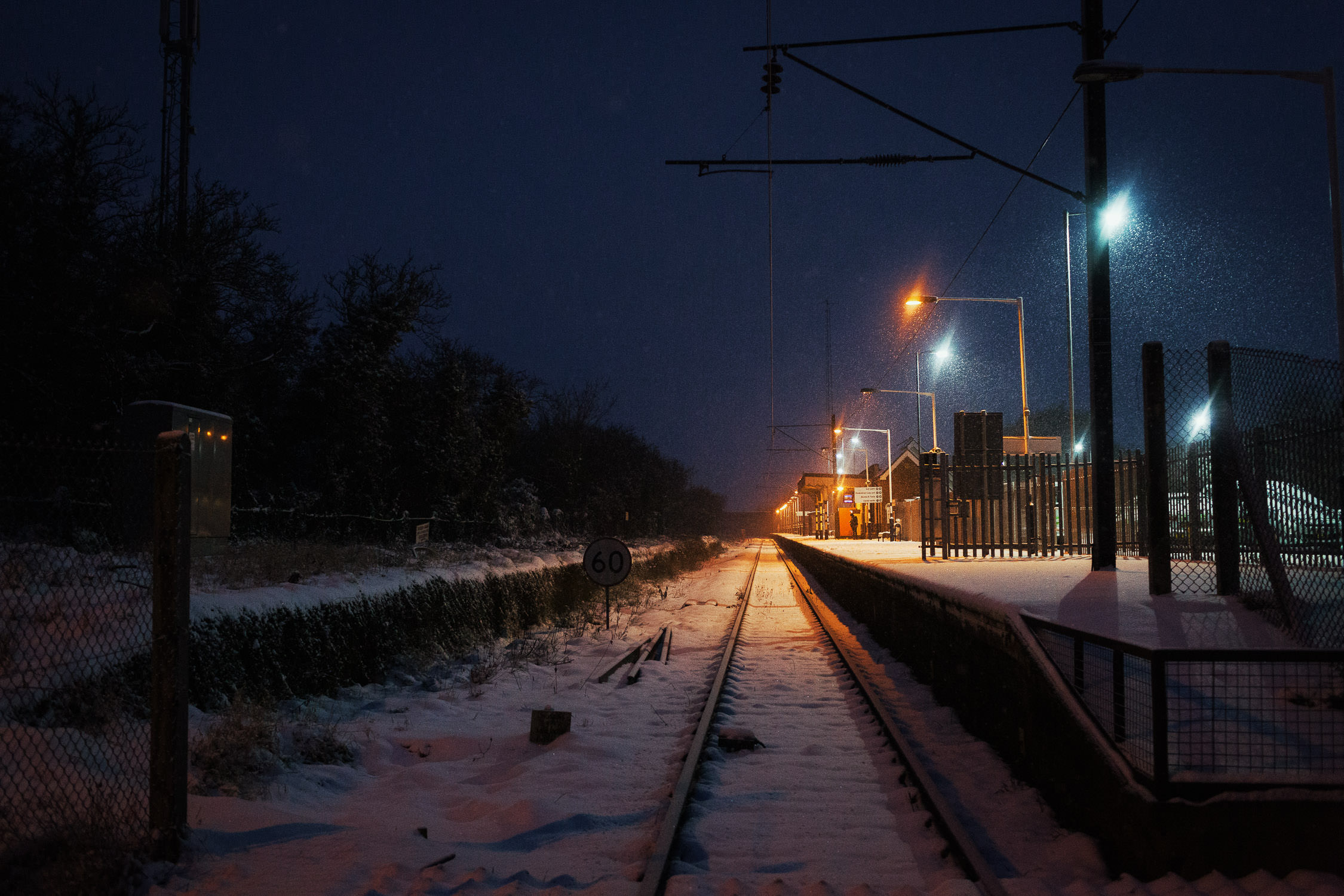 The railway line in South Woodham Ferrers in Essex. It is snowing at night.