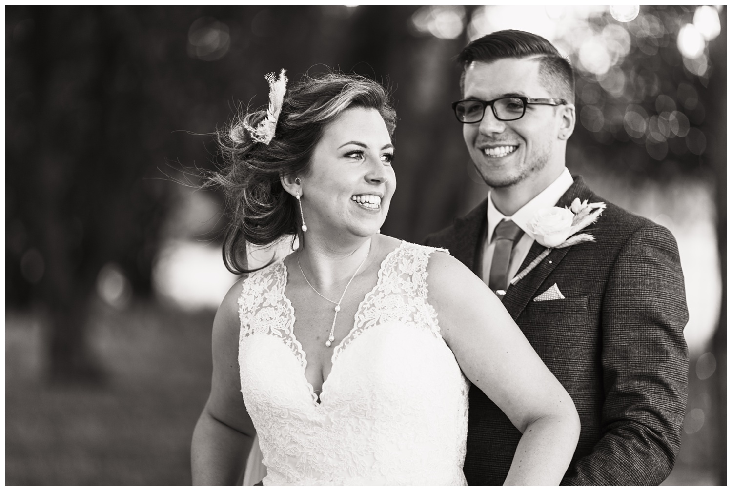 A portrait of a bride and groom. The bride is the foreground and smiling naturally.