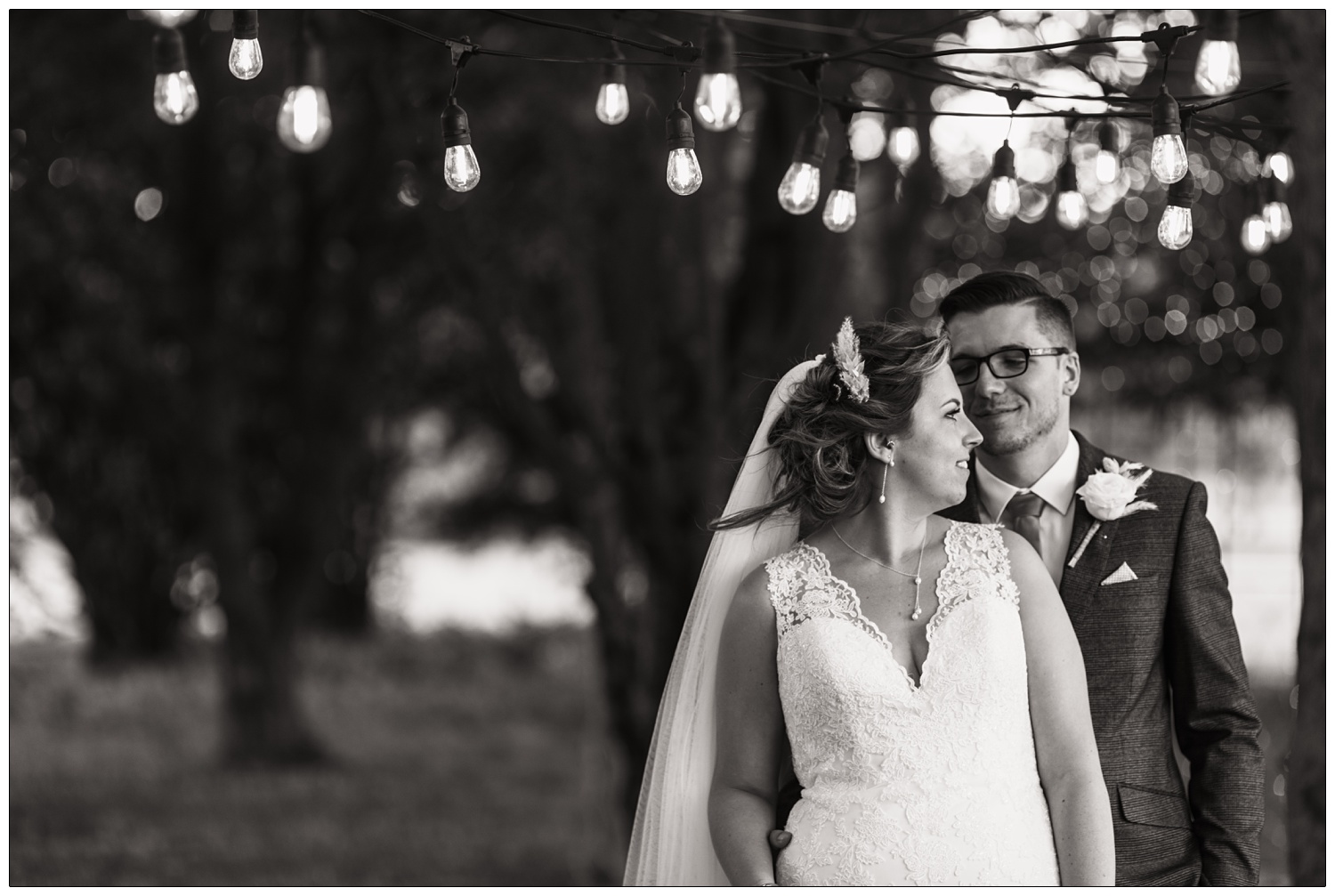 Bride and groom portraits under a string of lightbulbs hanging between the trees. Fynn Valley Terrace wedding.