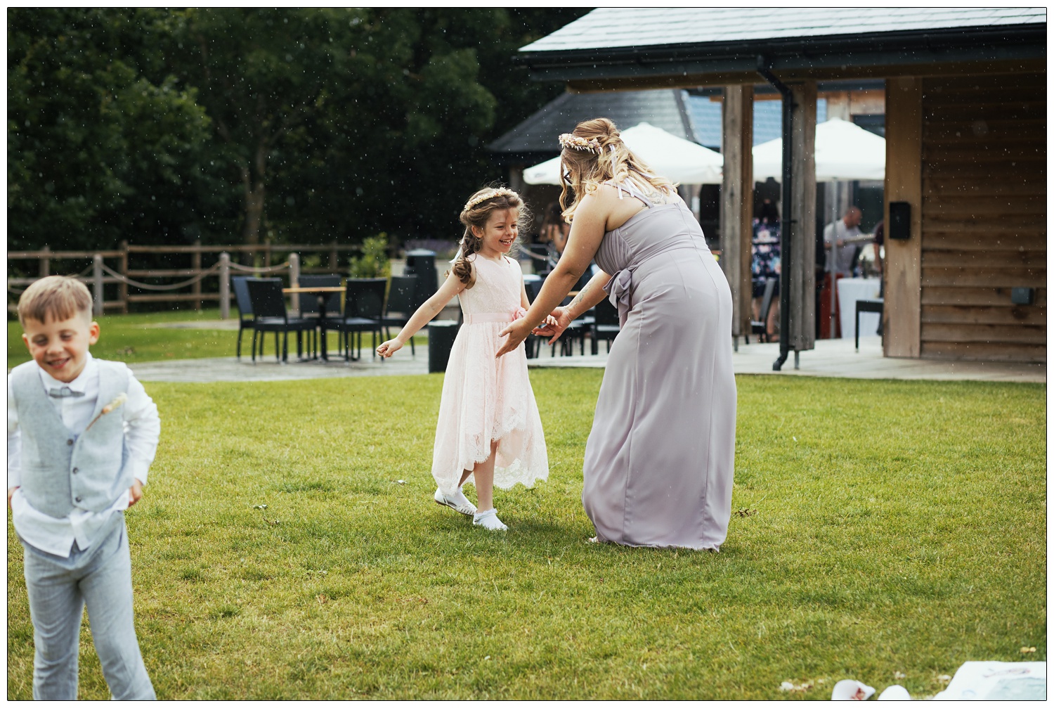 A bridesmaid and flower girl dance in the rain at a Fynn Valley Terrace wedding.