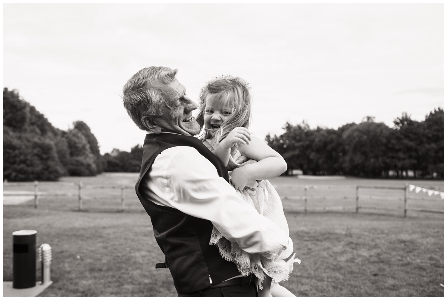 A grandad smiles as he hugs his granddaughter as she laughs. At an Ipswich wedding.