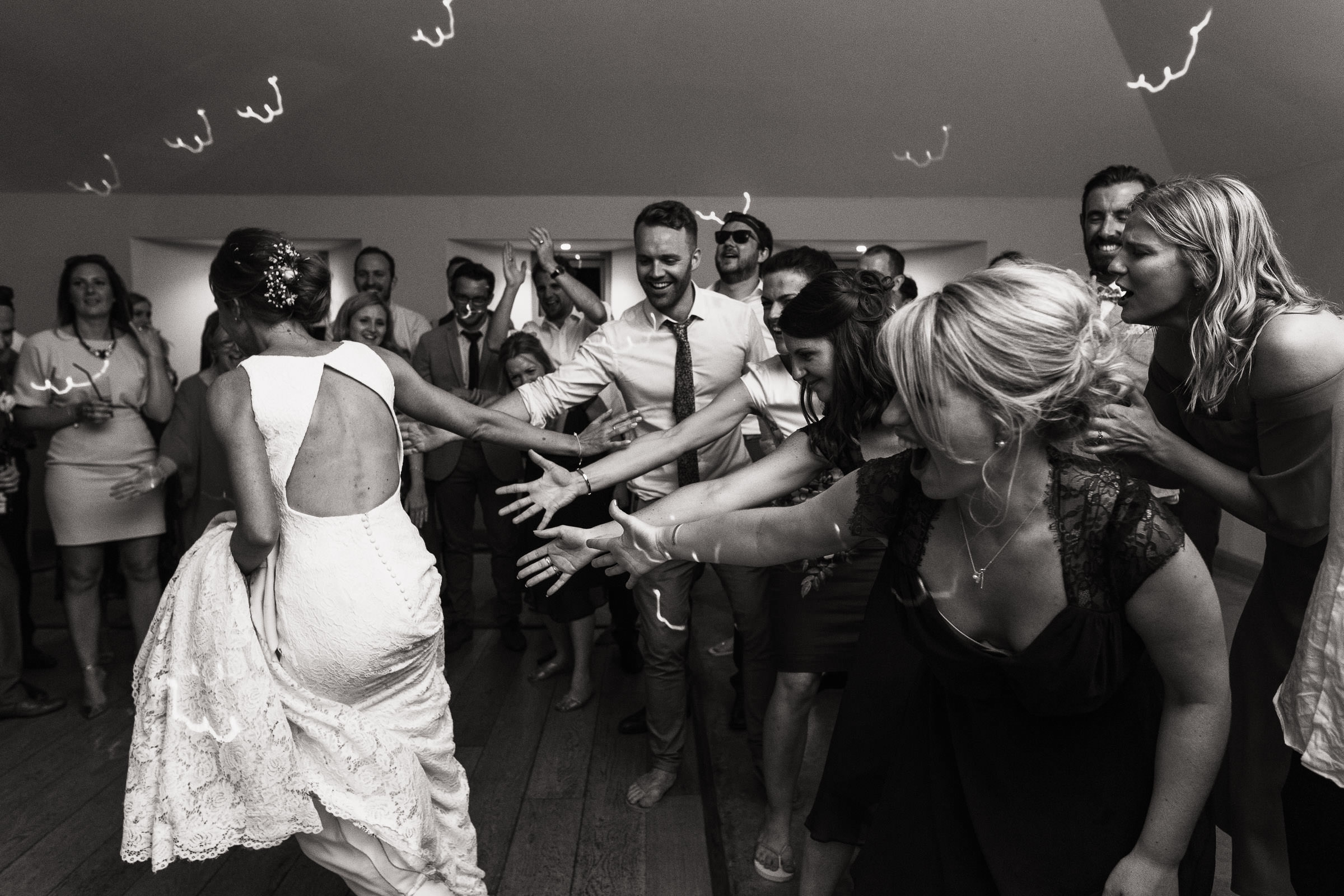A bride running around the dance floor at Houchins. The guests reach out as she passes by.