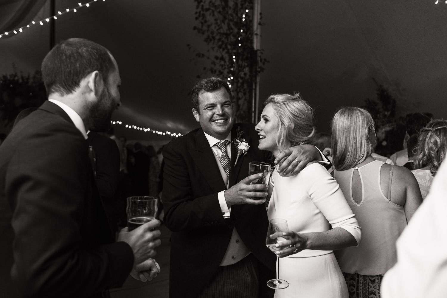 Bride and groom together holding drinks at the reception a Sail & Cloth marquee.