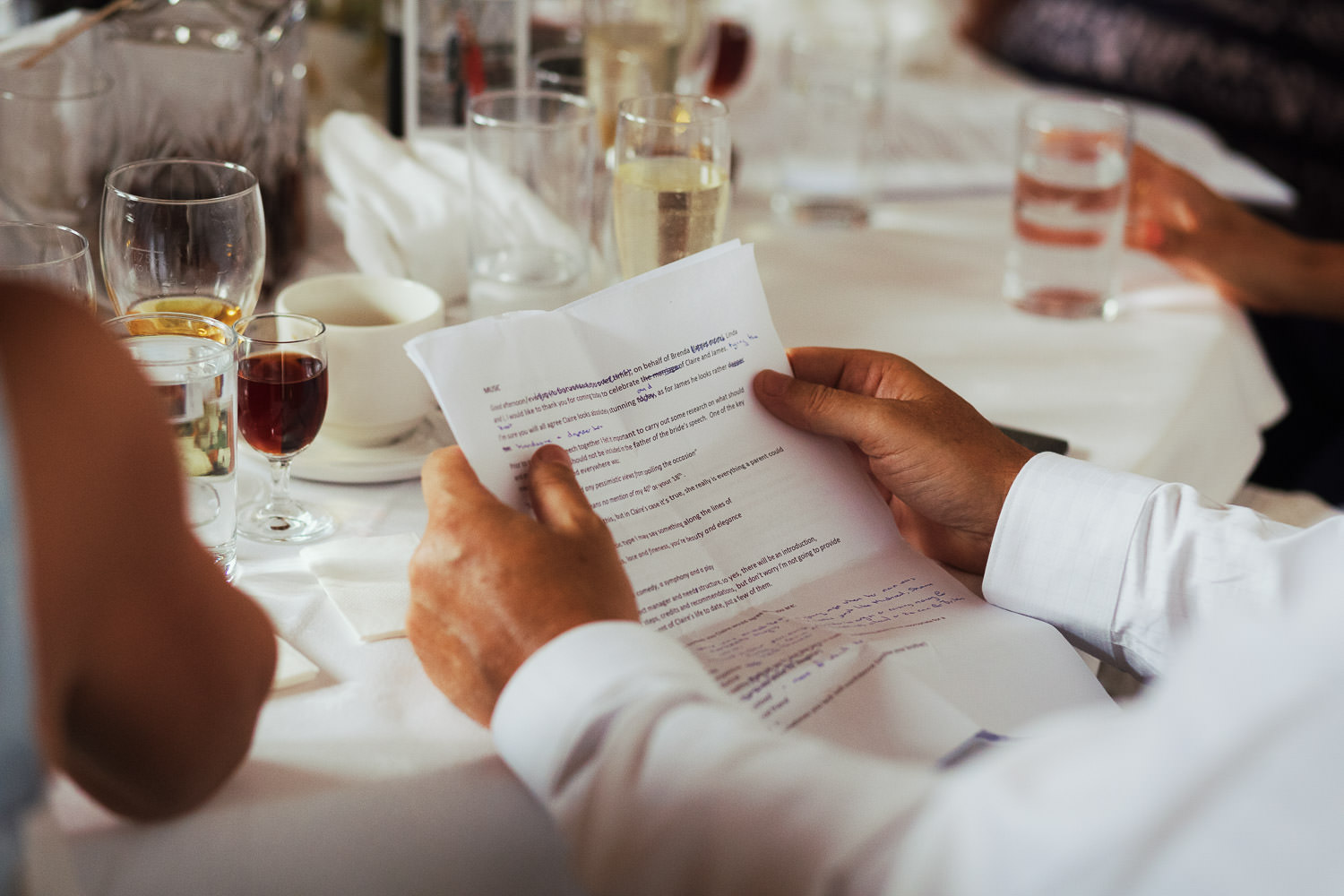 A father's hands holding his speech at a wedding.