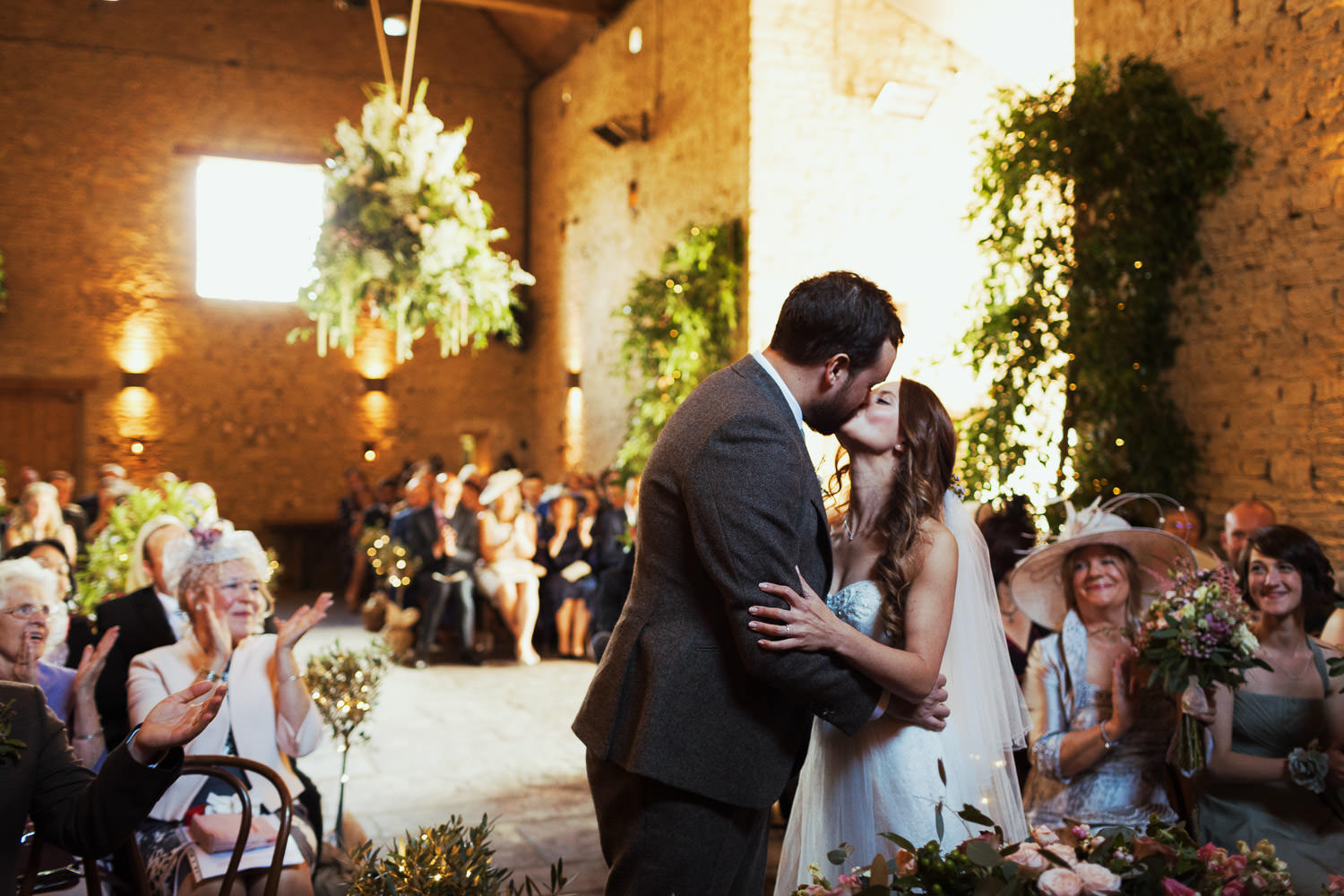 Bride and groom kiss during a wedding ceremony at Cripps Barn.