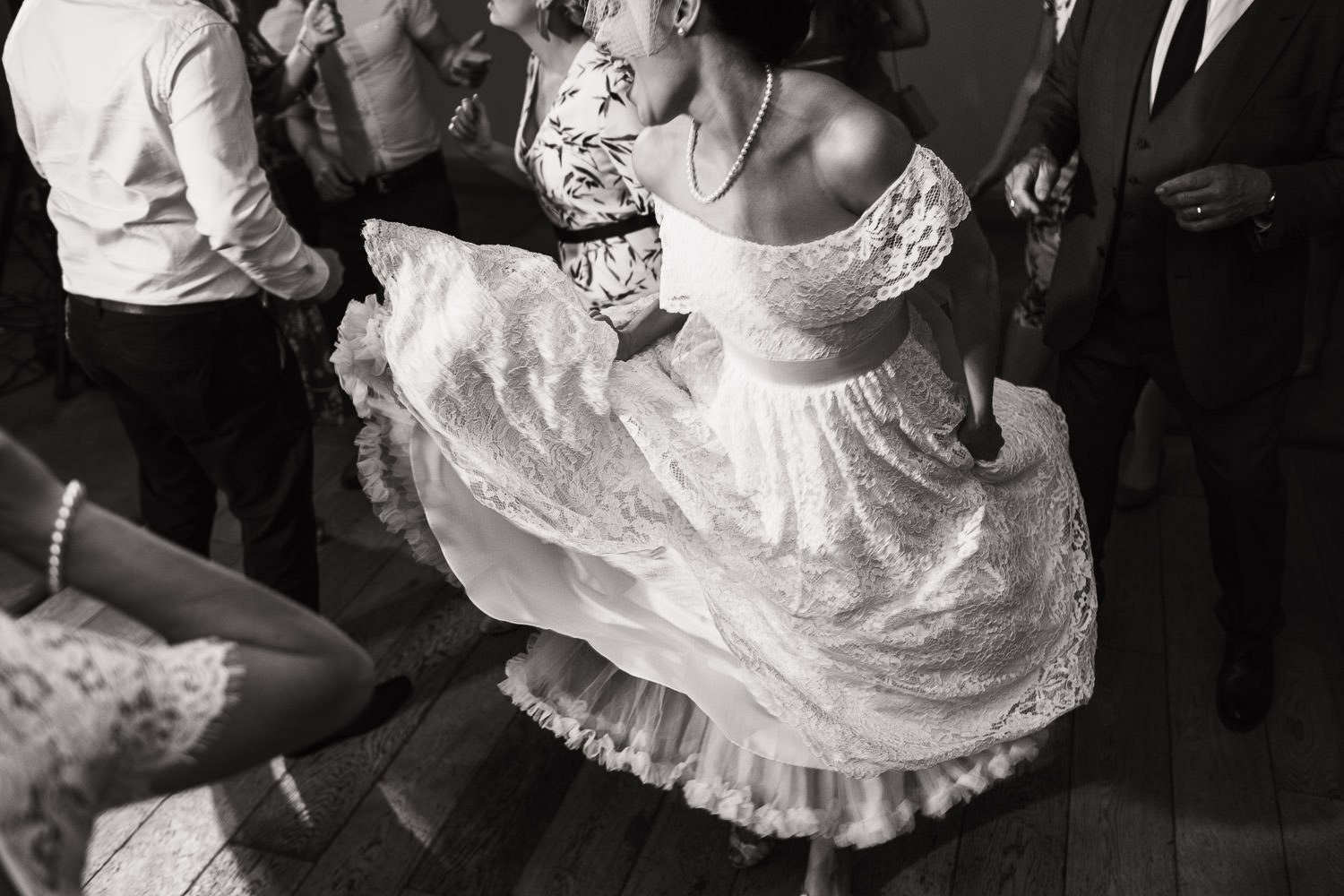 The bride dressed in a vintage style off the shoulder lace dress is dancing. She is holding her dress and singing.