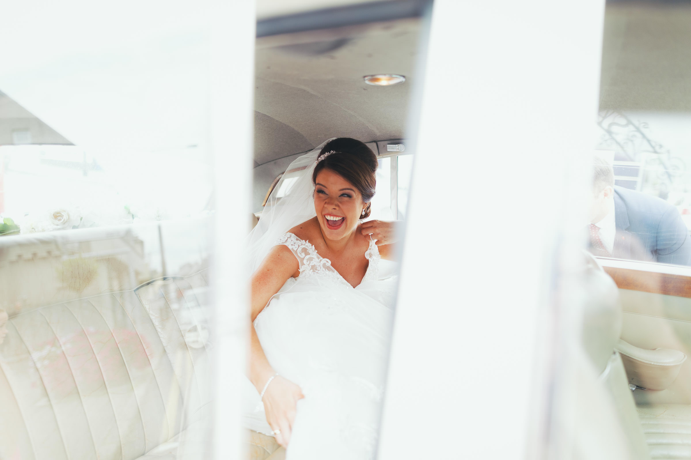 View through the car door of the bride laughing after her wedding.
