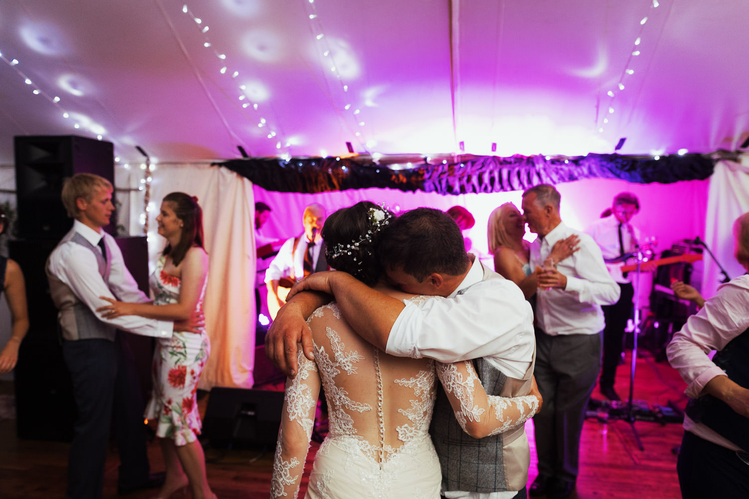 Man hugging his wife at wedding reception.