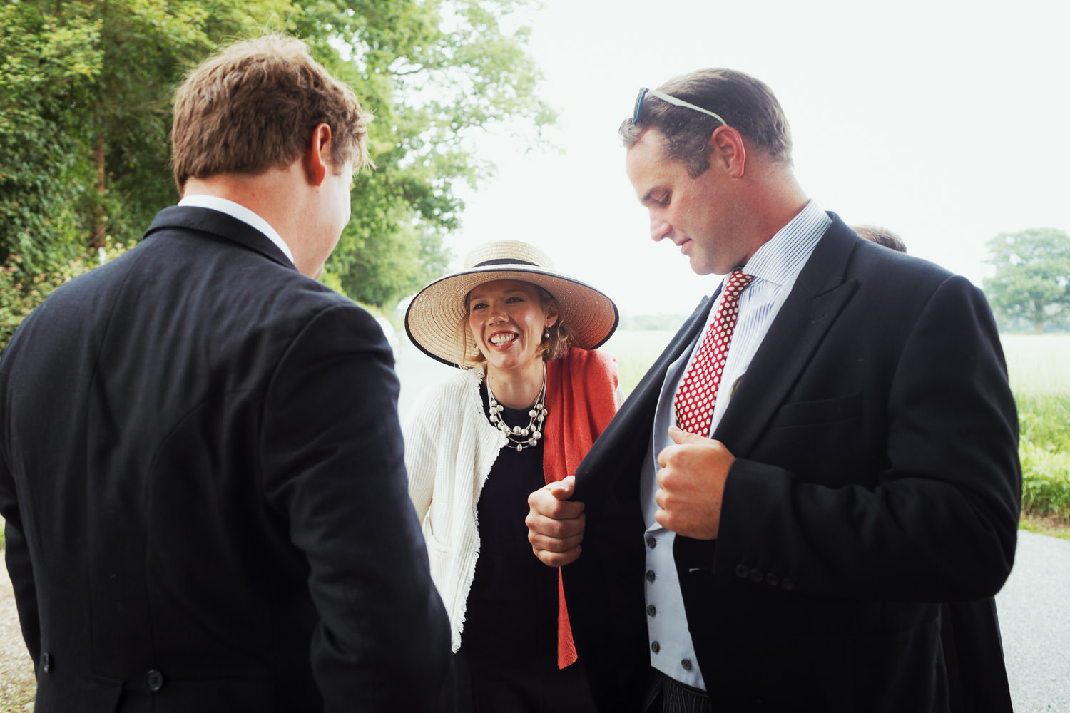 A woman in a hat arriving at a wedding.