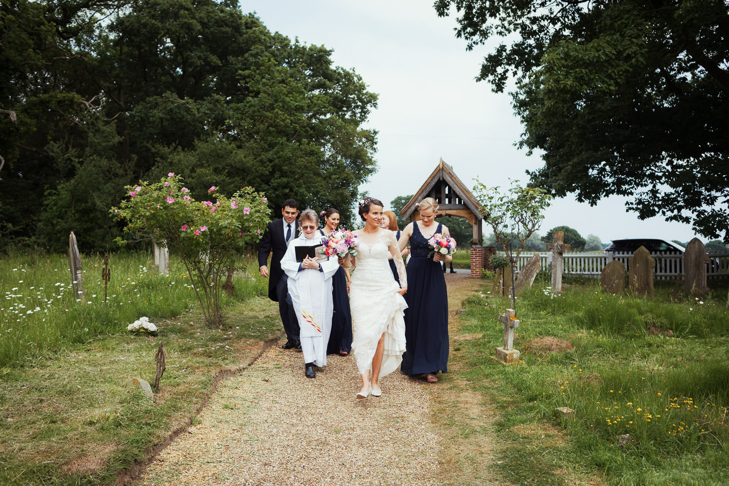 Bride approaching the church in Great Totham with the vicar and bridesmaids.