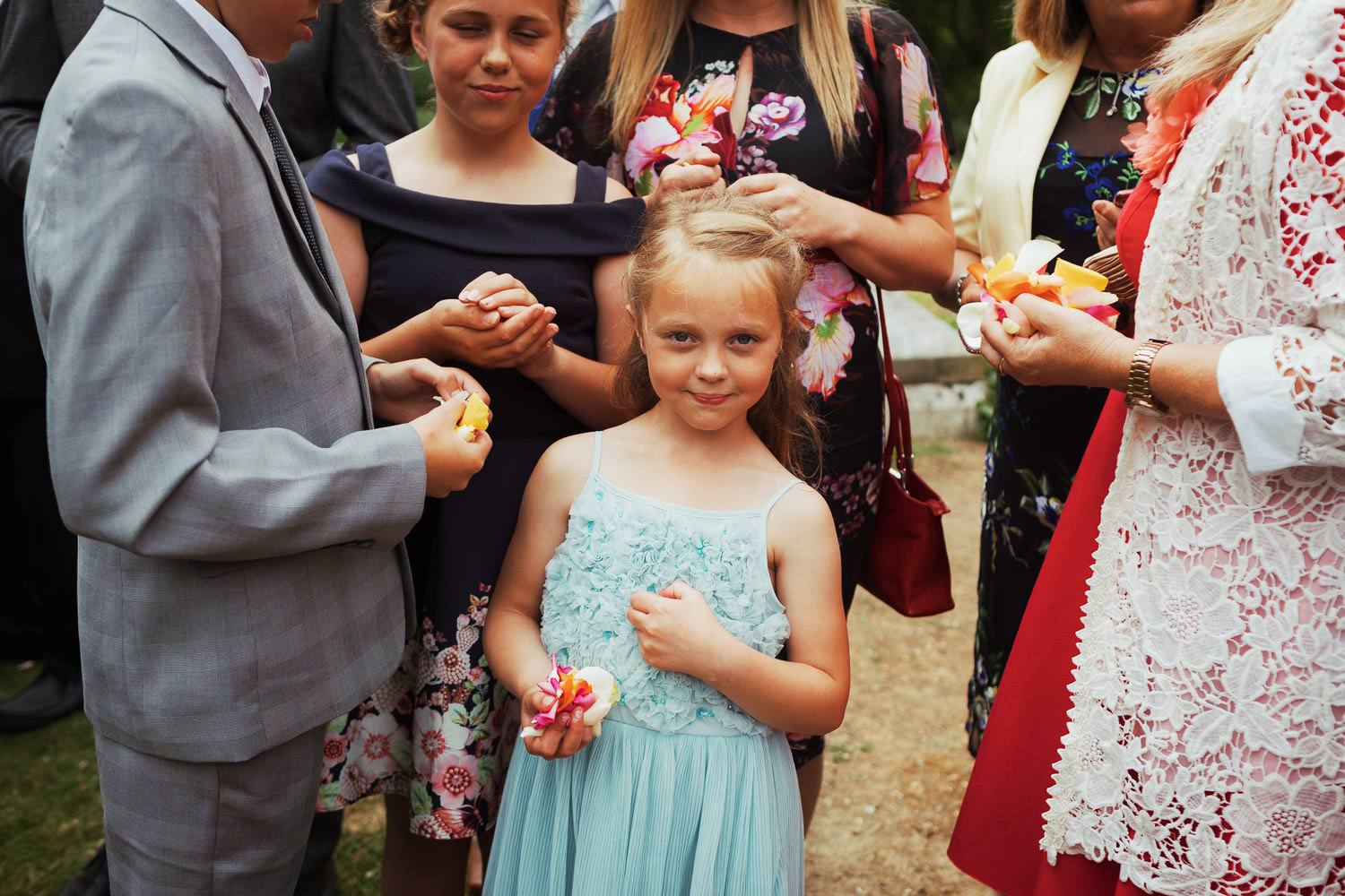 A young girl holding petals for confetti throwing, looking at the camera.