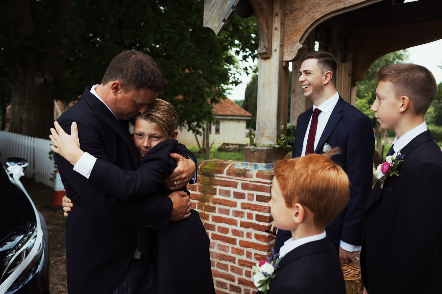 Groom hugging some younger wedding guests outside the church in Great Totham, Maldon.