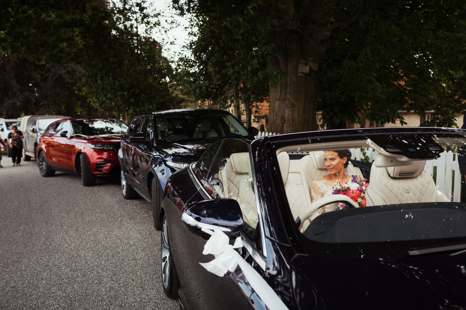 Bride sat in a convertible dark Mercedes with the roof down.