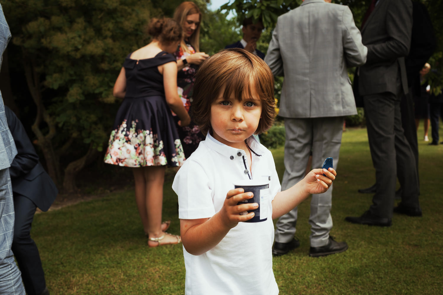 Little boy eating Rossi ice cream in a garden at a wedding in Great Totham.
