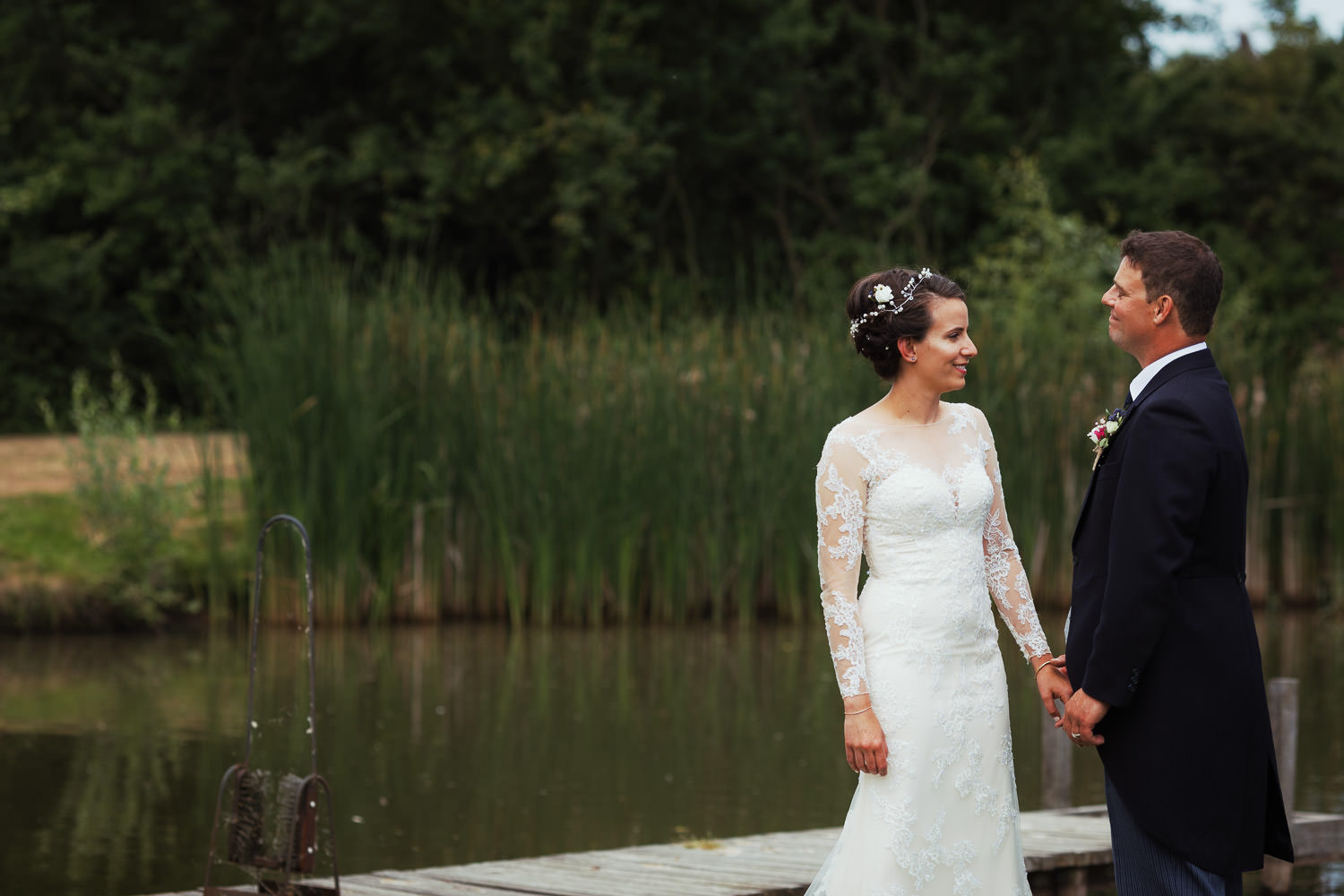 Bride and groom by a pond.