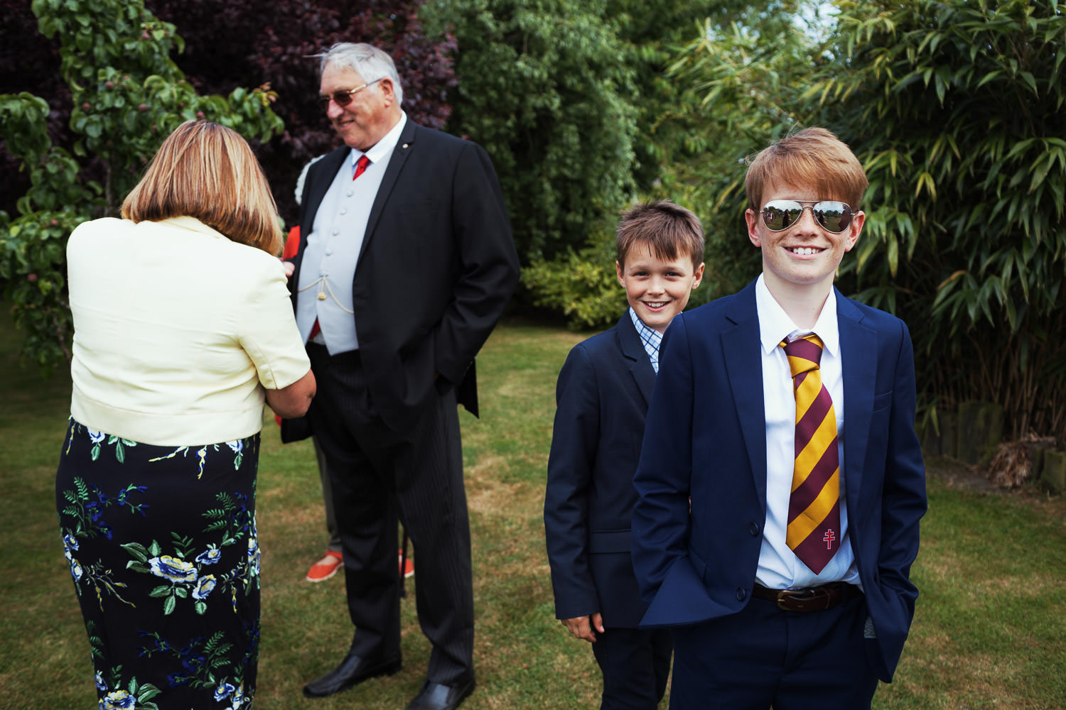 Two boys in suits smiling at the camera at a wedding in Essex.