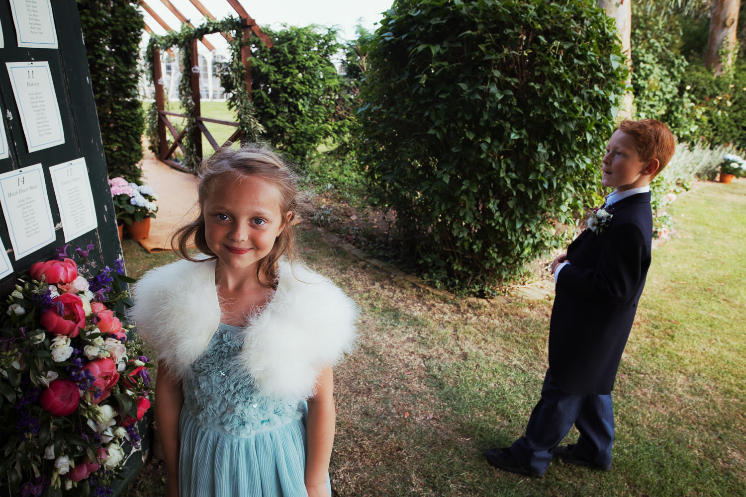 A young girl in a dress at a wedding looks at the camera.
