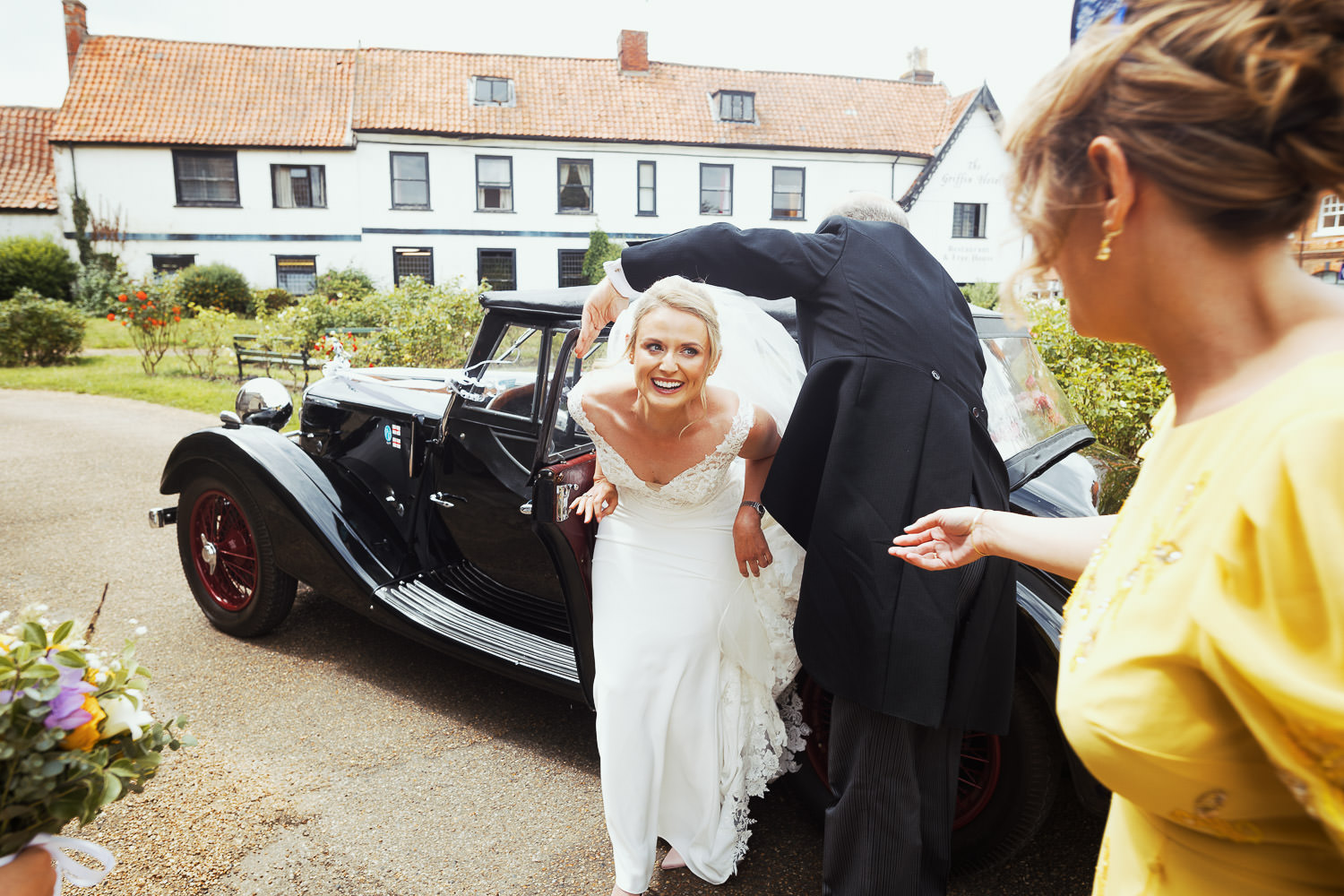 Bride getting out of the car, a 1938 Riley, for her wedding at St Mary's church in Attleborough.