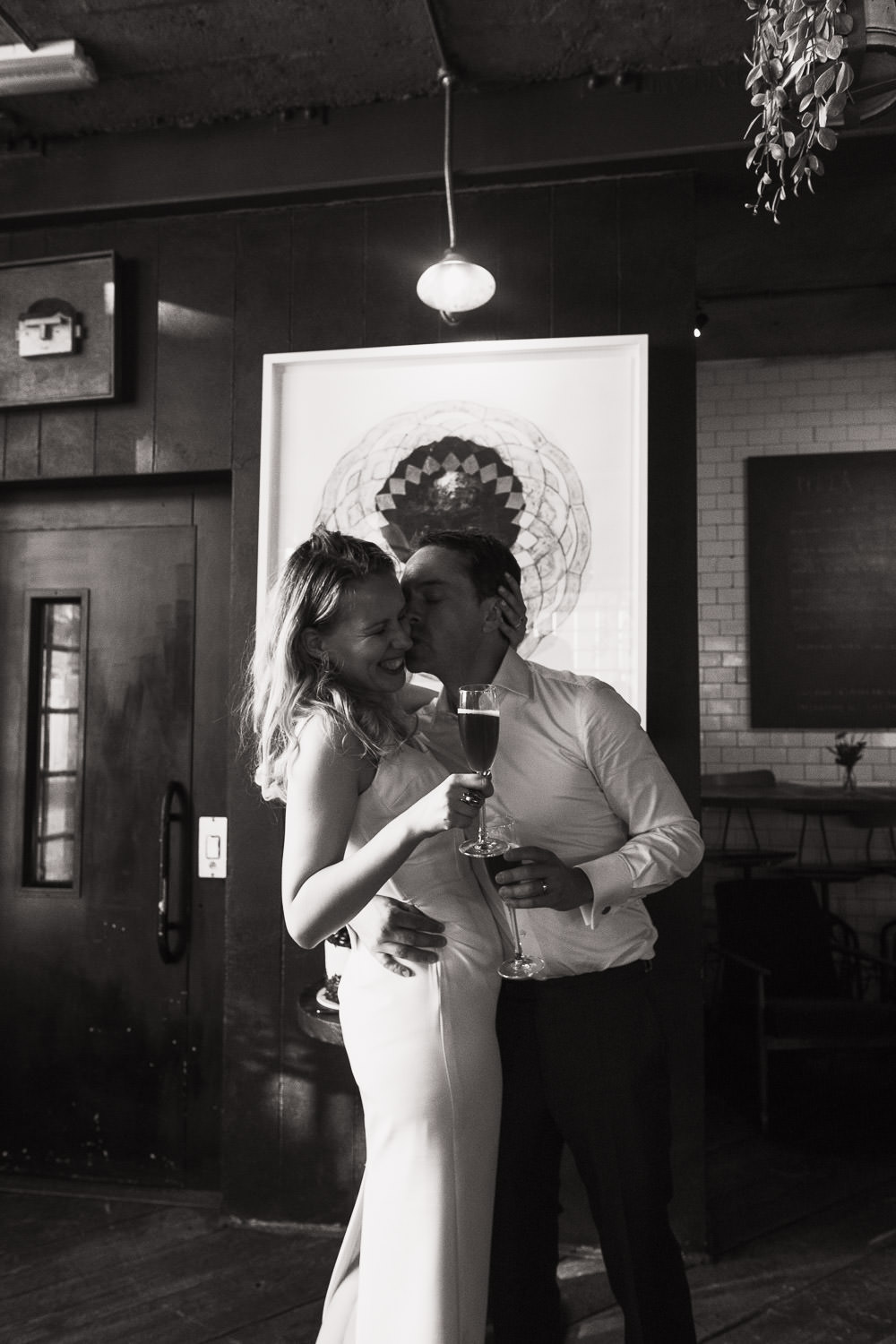 A candid photograph of a man kissing his wife at wedding reception at Never For Ever restaurant. London wedding.